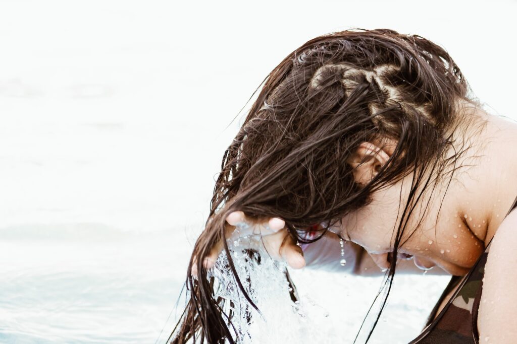A person getting their hair wet with water in the background