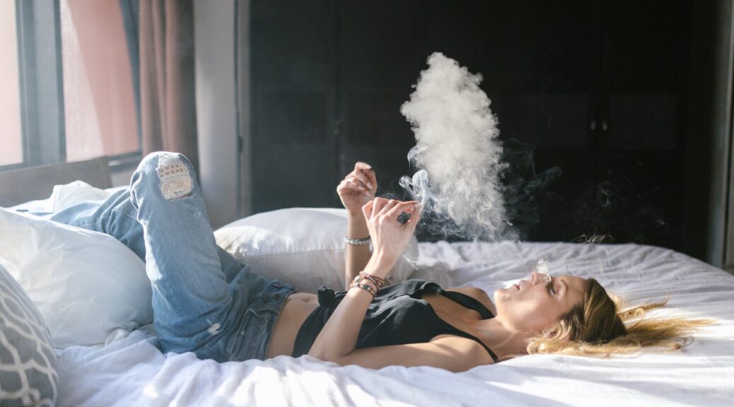 A person lying on a bed while smoking