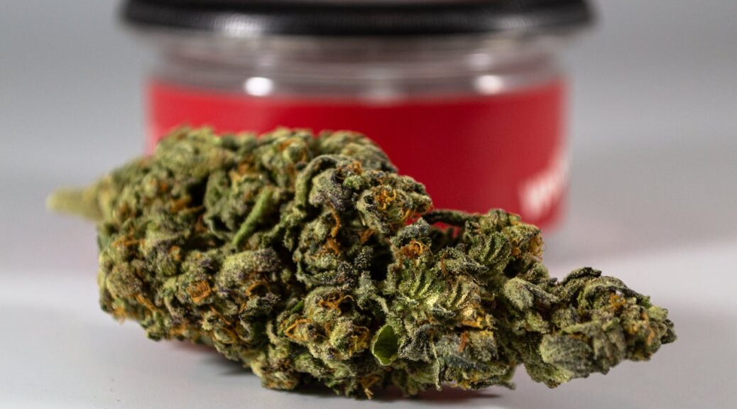 A nugget of cannabis in front of a red jar
